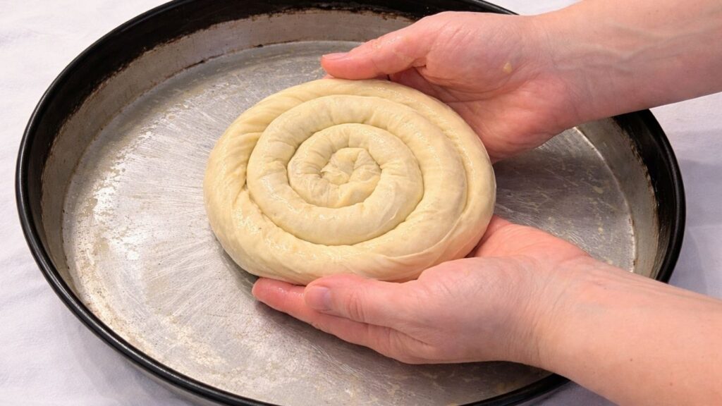 placing spiral potato borek into an oiled baking pan