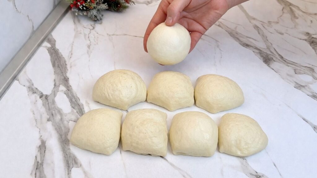 Rolling homemade pretzel dough into equal smooth balls on a work surface.