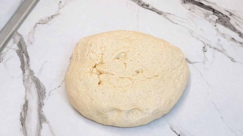 Homemade pretzel dough placed on a work surface ready for shaping.