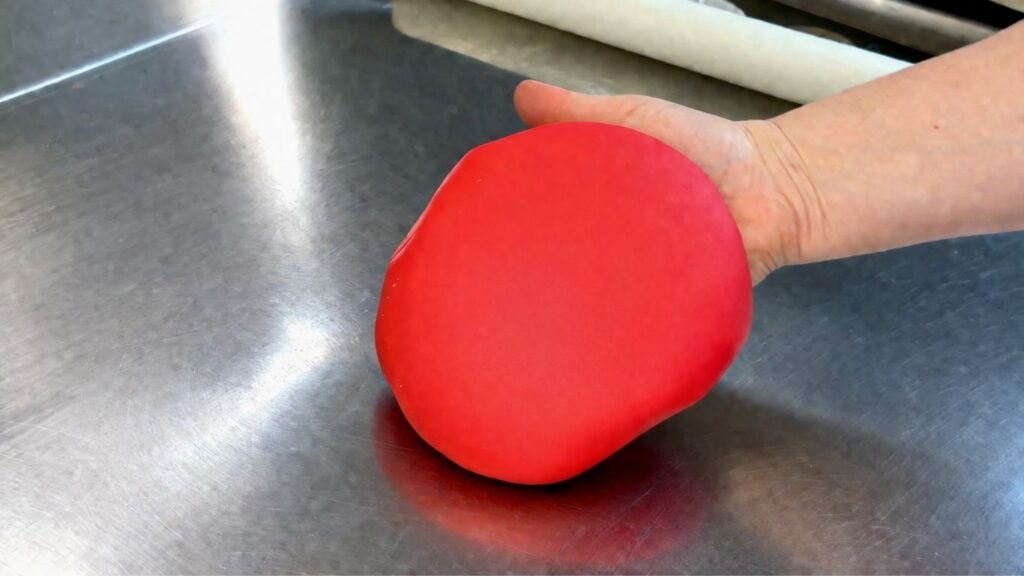 Kneaded red fondant in hand ready for covering a 40th birthday cake