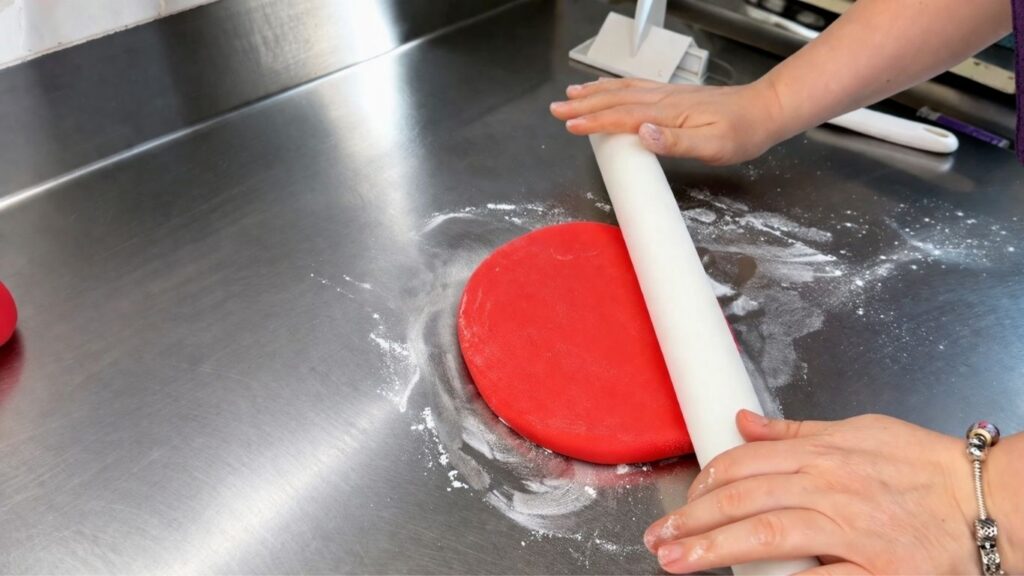 Rolling out red fondant with a rolling pin for a 40th birthday cake decorating tutorial