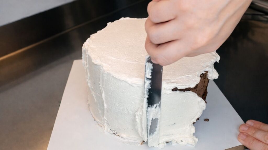 Applying buttercream to the middle tier of a 3-tier wedding cake