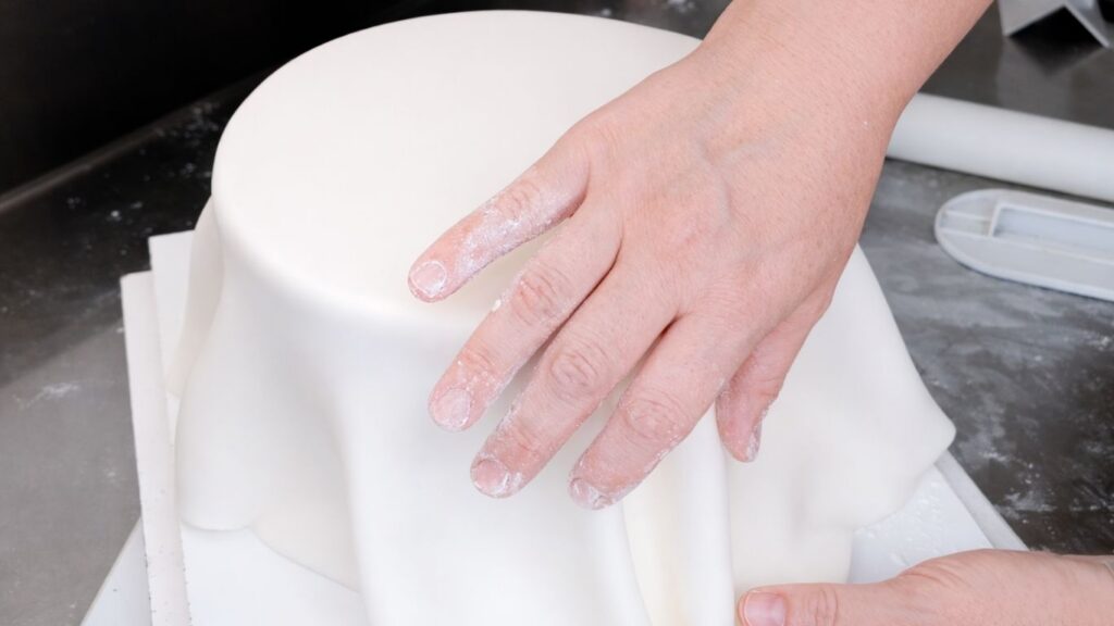 Covering a 3-tier wedding cake with fondant