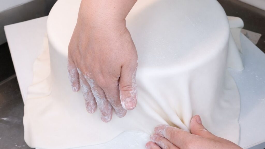 Covering a 3-tier wedding cake with fondant