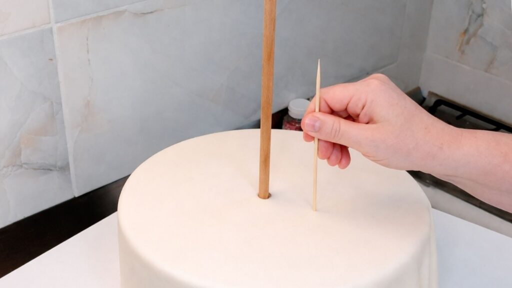 Inserting dowel rods into a 3-tier wedding cake for stability