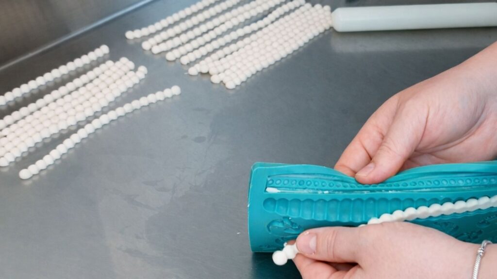 Making fondant pearls in a silicone mold for a 3-tier wedding cake