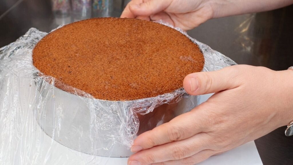 Chocolate cake layers in the pan, filled with chocolate cream and ready to be stacked for a candy cake.