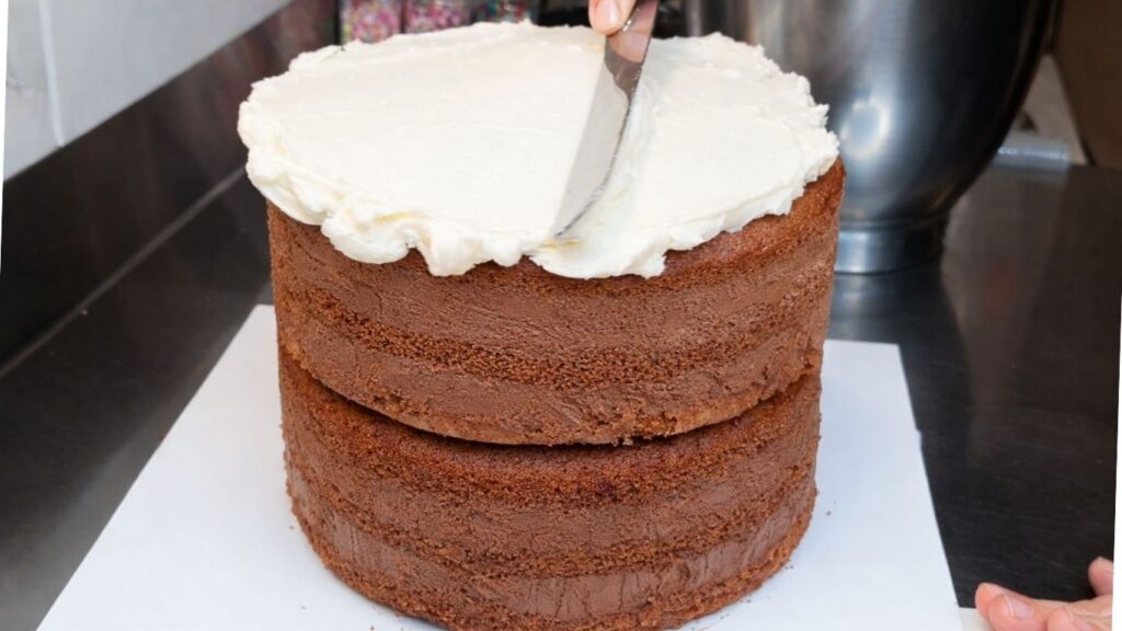 Spreading buttercream on top of the cake to create a smooth base for the candy cake decoration
