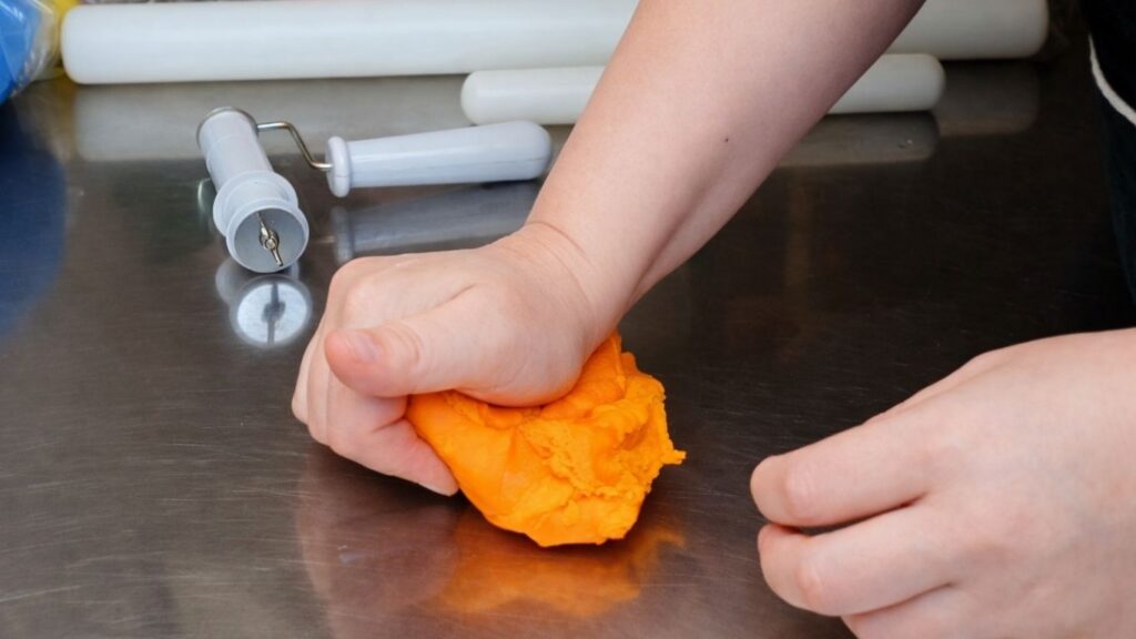 Rolling fondant by hand into an even rope for candy cake decorations and toppers.