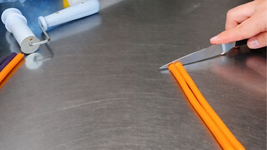 Rolling fondant into a log to prepare it for shaping and cutting candy cake bands.