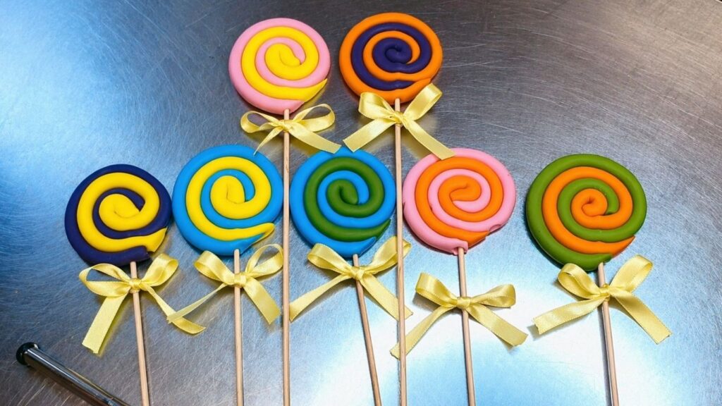 Fondant lollipop toppers with satin ribbon bows, ready to place on the candy cake
