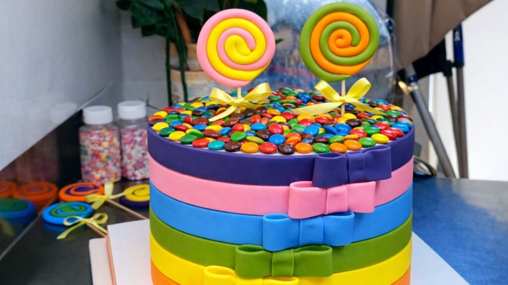 Placing the lollipop toppers into the cake to complete the candy cake decoration.