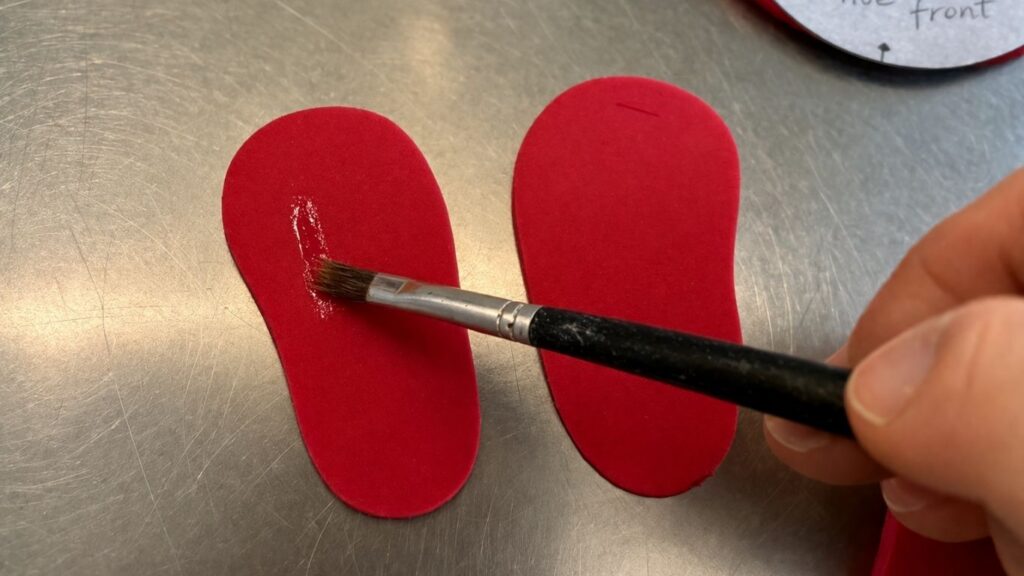 Brushing water onto fondant baby shoes sole pieces to attach in-sole as edible glue
