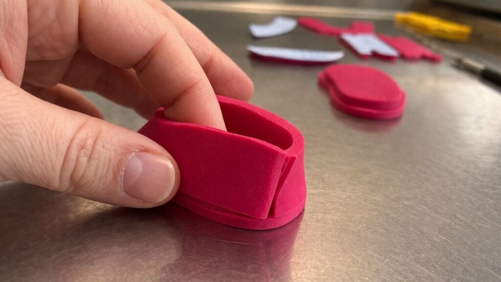 Pink fondant baby shoes with upper part attached to sole ready for next step