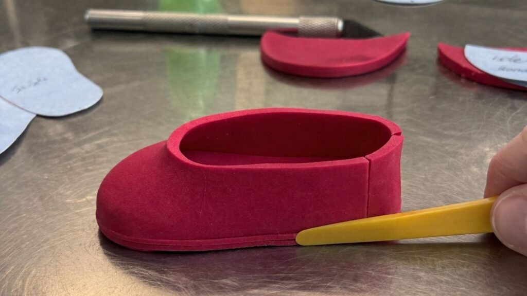 Pink fondant baby shoes with upper part attached to sole ready for next step