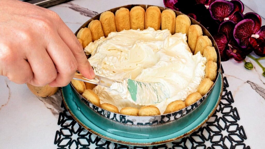 Spreading and smoothing the cream filling over ladyfingers for no-bake lemon cake