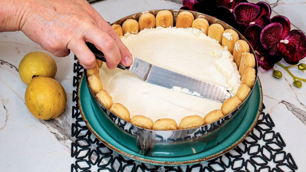 Spreading and smoothing the cream filling over ladyfingers for no-bake lemon cake
