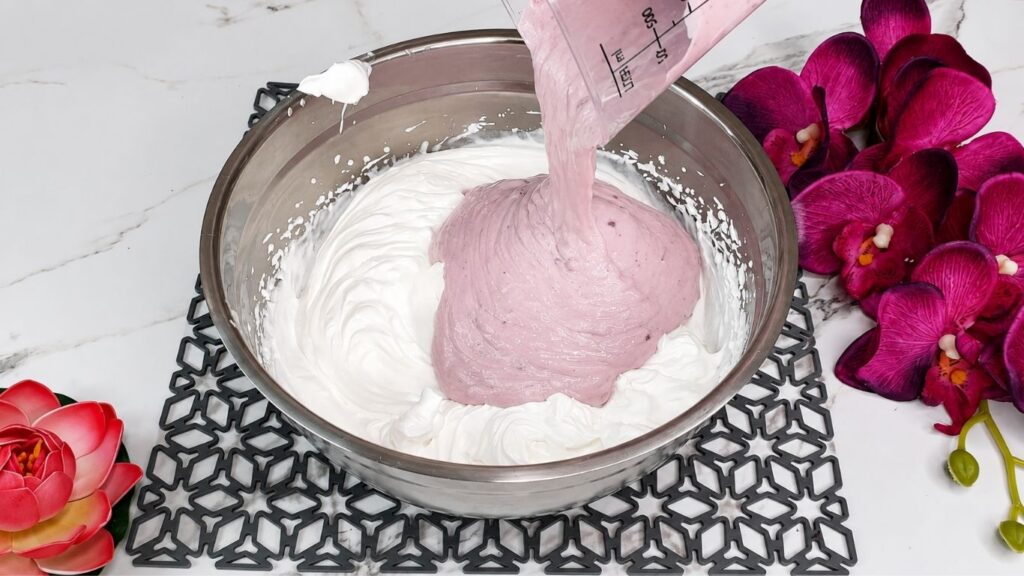 Whipping heavy cream and mixing with yogurt and ingredients for easy no bake raspberry yogurt cake filling