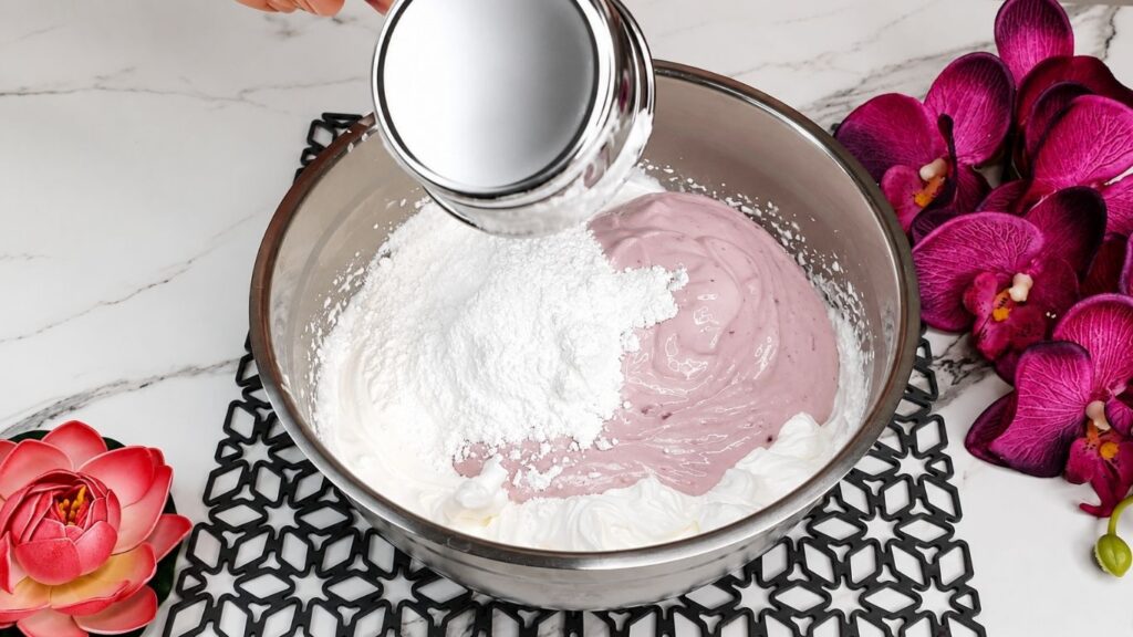 Whipping heavy cream and mixing with yogurt and ingredients for easy no bake raspberry yogurt cake filling