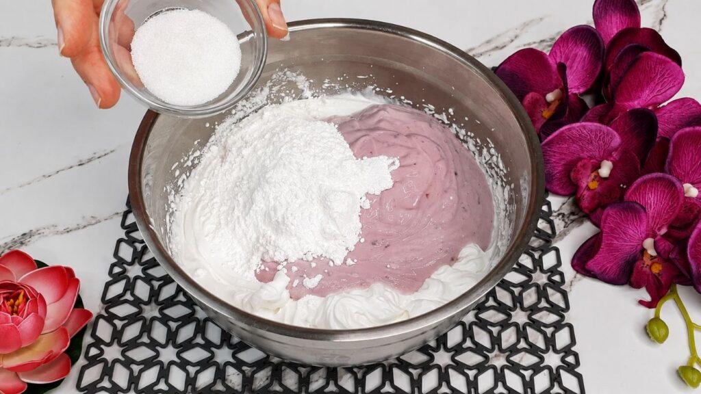 Whipping heavy cream and mixing with yogurt and ingredients for easy no bake raspberry yogurt cake filling