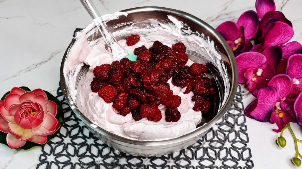 Whipping heavy cream and mixing with yogurt and ingredients for easy no bake raspberry yogurt cake filling