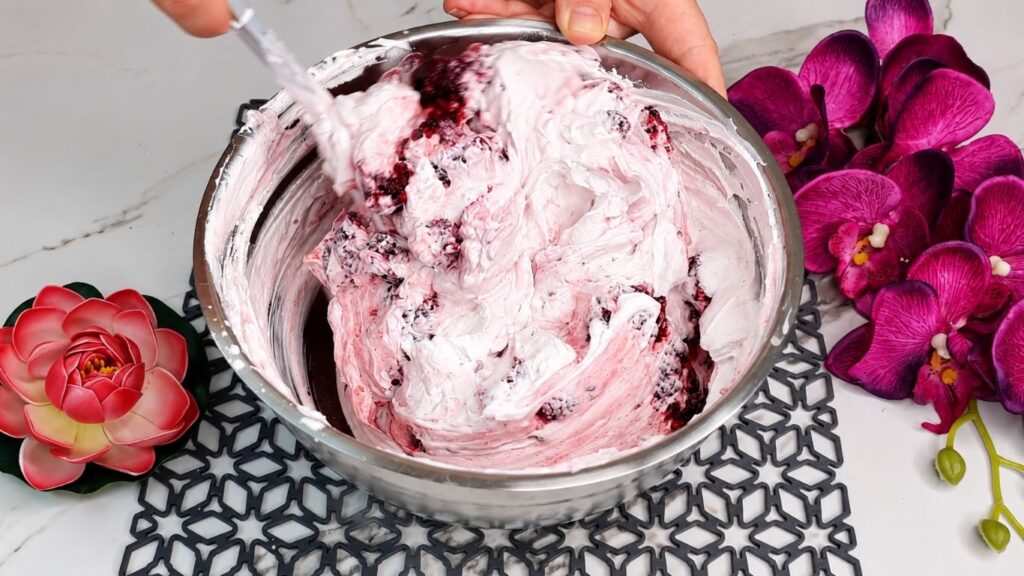 Whipping heavy cream and mixing with yogurt and ingredients for easy no bake raspberry yogurt cake filling