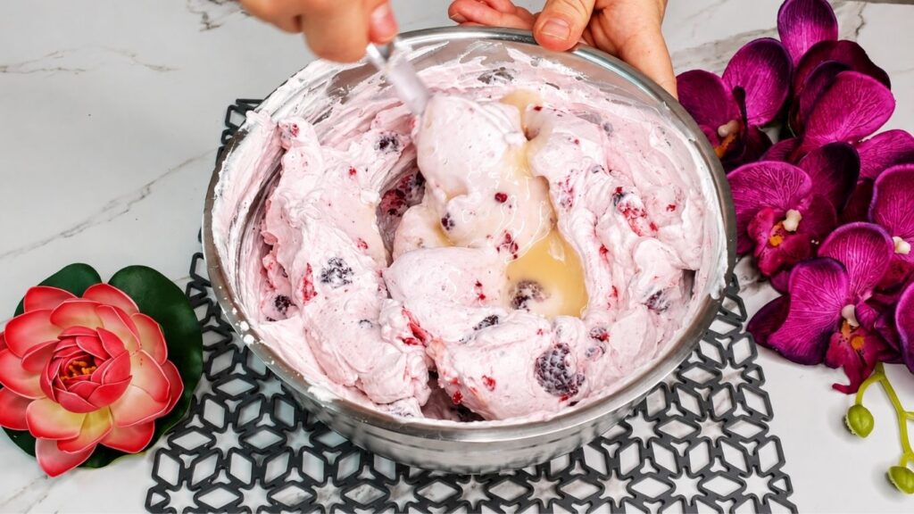 Whipping heavy cream and mixing with yogurt and ingredients for easy no bake raspberry yogurt cake filling
