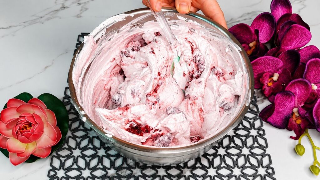 Whipping heavy cream and mixing with yogurt and ingredients for easy no bake raspberry yogurt cake filling
