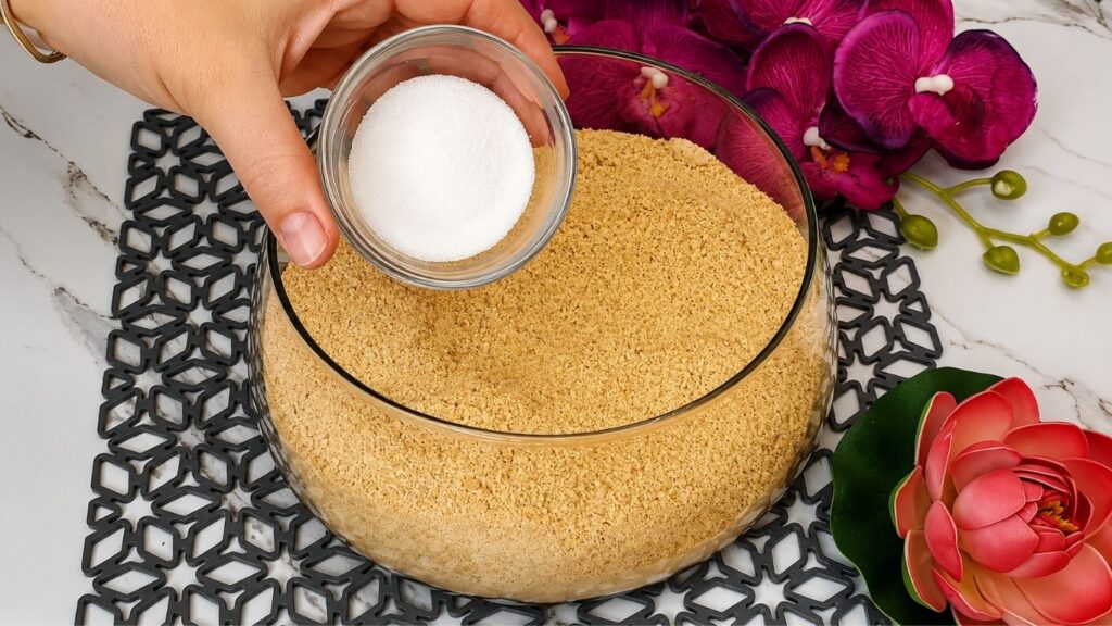 Mixing crushed graham crackers with milk and sugar for no bake raspberry yogurt cake recipe crust base