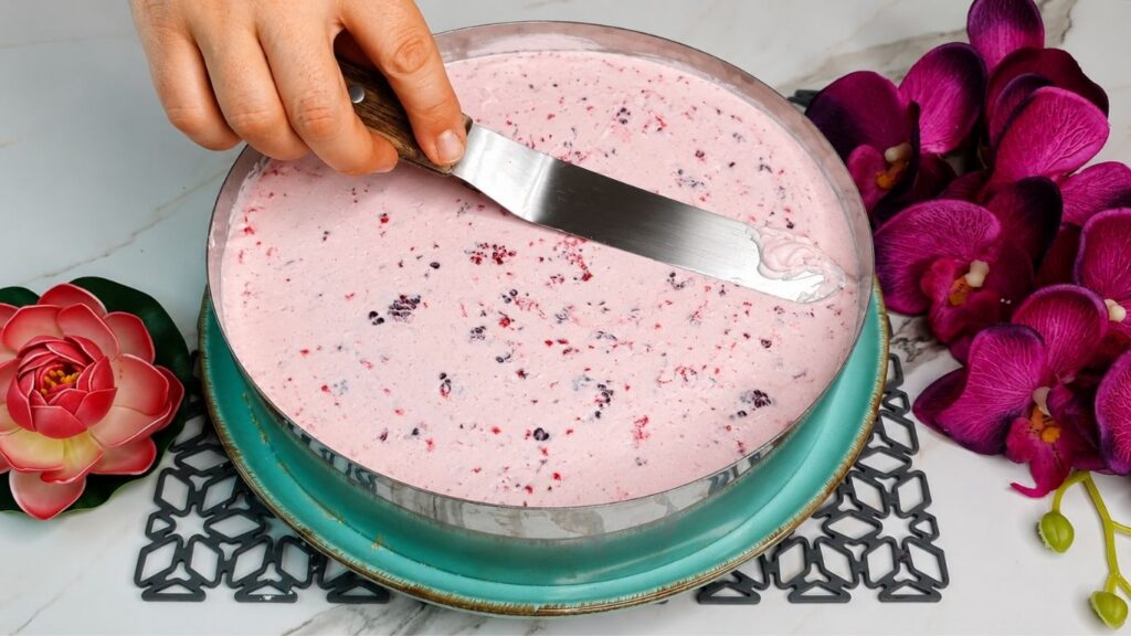Whipping heavy cream and mixing with yogurt and ingredients for easy no bake raspberry yogurt cake filling