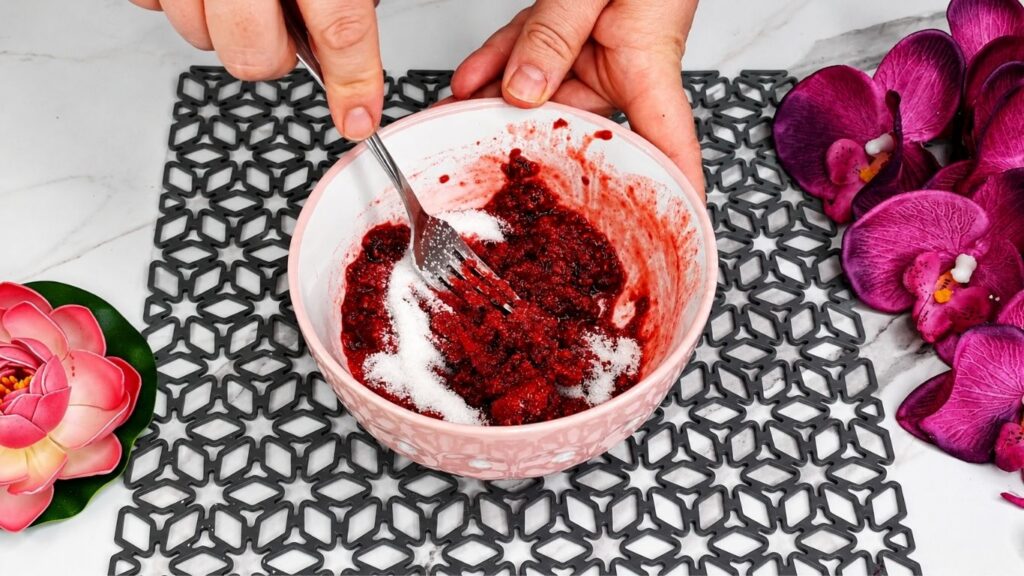 Crushing fresh raspberries with sugar and water for easy no bake raspberry yogurt cake glaze topping