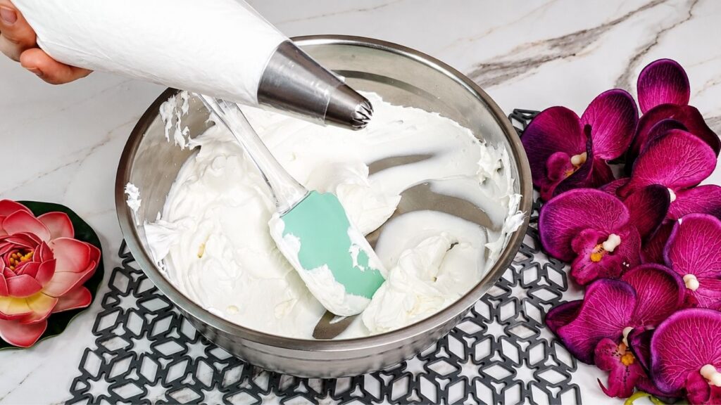 Decorating easy no bake raspberry yogurt cake with whipped cream fresh raspberries and mint leaves