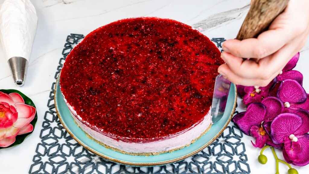 Decorating easy no bake raspberry yogurt cake with whipped cream fresh raspberries and mint leaves