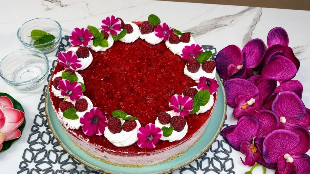 Decorating easy no bake raspberry yogurt cake with whipped cream fresh raspberries and mint leaves