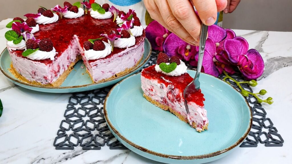 Sliced easy no bake raspberry yogurt cake on serving plate showing layers and fresh raspberry garnish