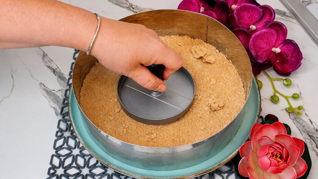 Pressing graham cracker mixture into springform pan for easy no bake raspberry yogurt cake crust base