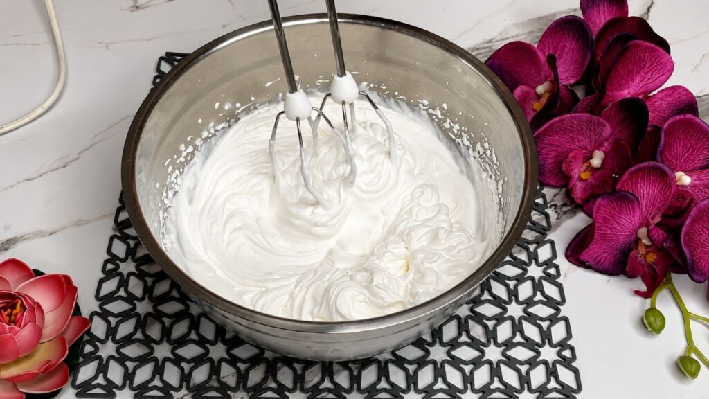 Whipping heavy cream and mixing with yogurt and ingredients for easy no bake raspberry yogurt cake filling