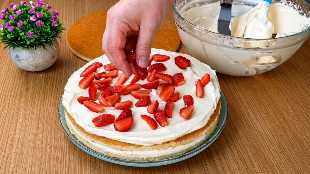 Adding fresh chopped strawberries over the second layer of vanilla cream for easy strawberry cake filling