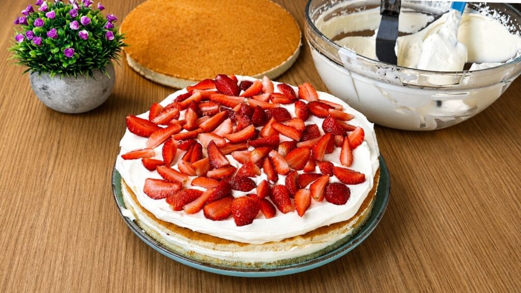 Adding fresh chopped strawberries over the second layer of vanilla cream for easy strawberry cake filling