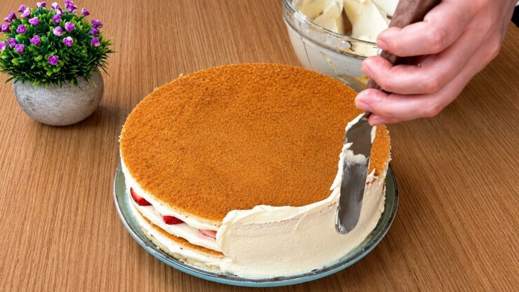Covering the easy strawberry cake with smooth vanilla cream before final decoration