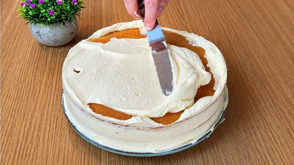 Covering the easy strawberry cake with smooth vanilla cream before final decoration