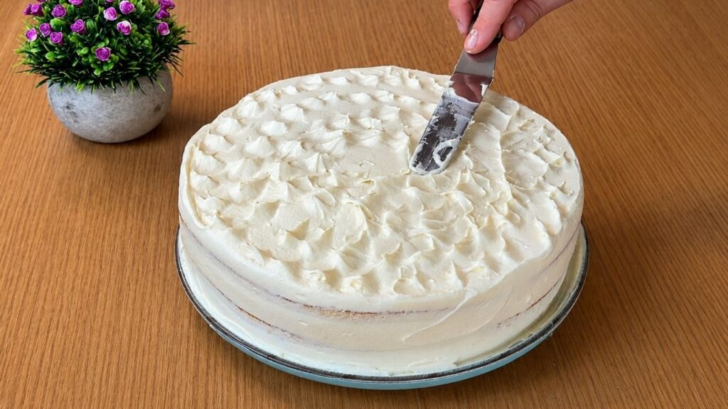Covering the easy strawberry cake with smooth vanilla cream before final decoration