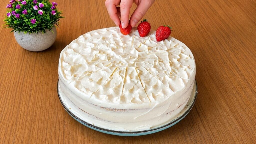 Decorating each marked slice of easy strawberry cake with fresh whole strawberries
