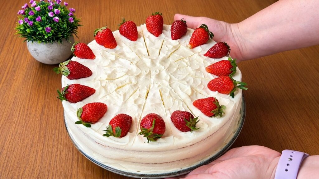 Homemade easy strawberry cake decorated with fresh strawberries held on a cake stand ready for serving