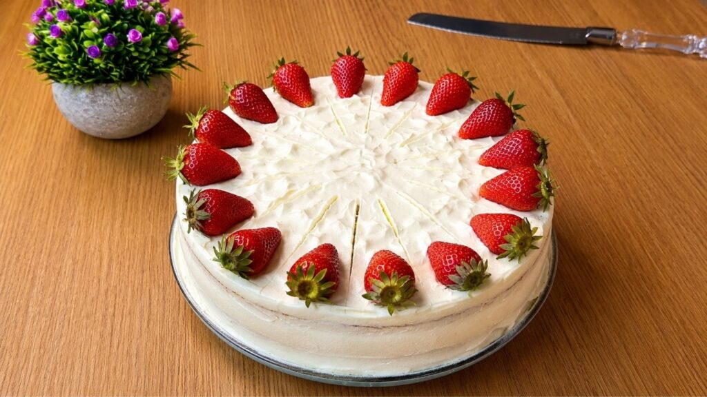 Finished easy strawberry cake decorated with fresh strawberries and creamy vanilla frosting ready to serve