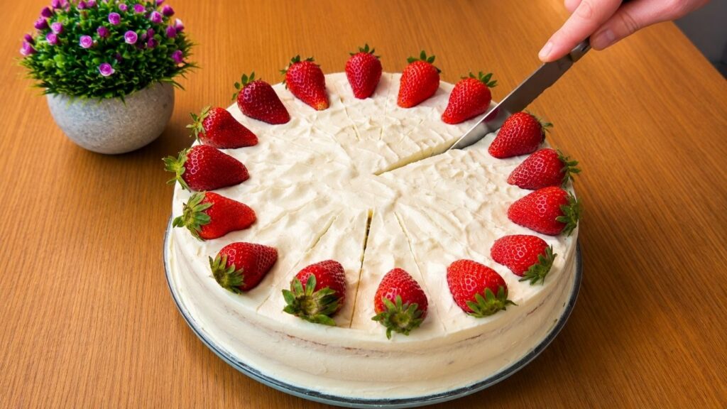 Cutting a slice of easy strawberry cake with fresh strawberries and creamy vanilla filling