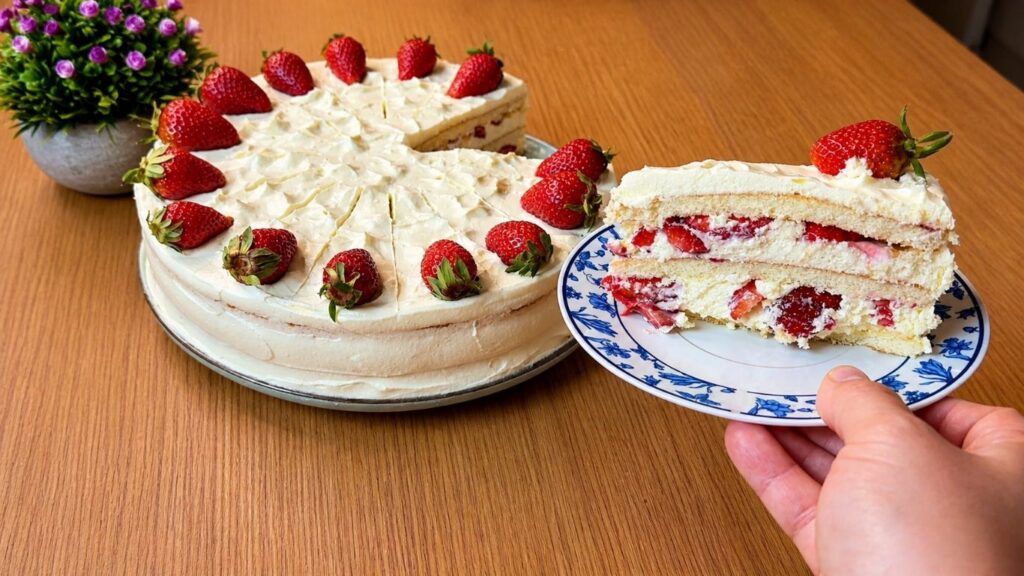 Slice of easy strawberry cake on a dessert plate with creamy vanilla filling and fresh strawberries inside
