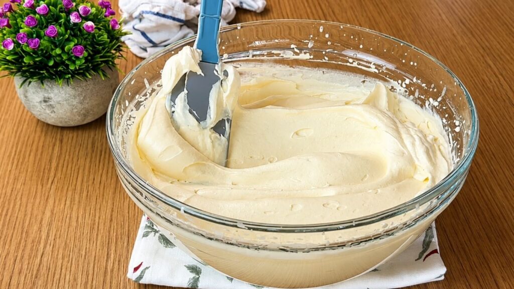 Smooth and fluffy vanilla cream prepared for easy strawberry cake in a glass mixing bowl