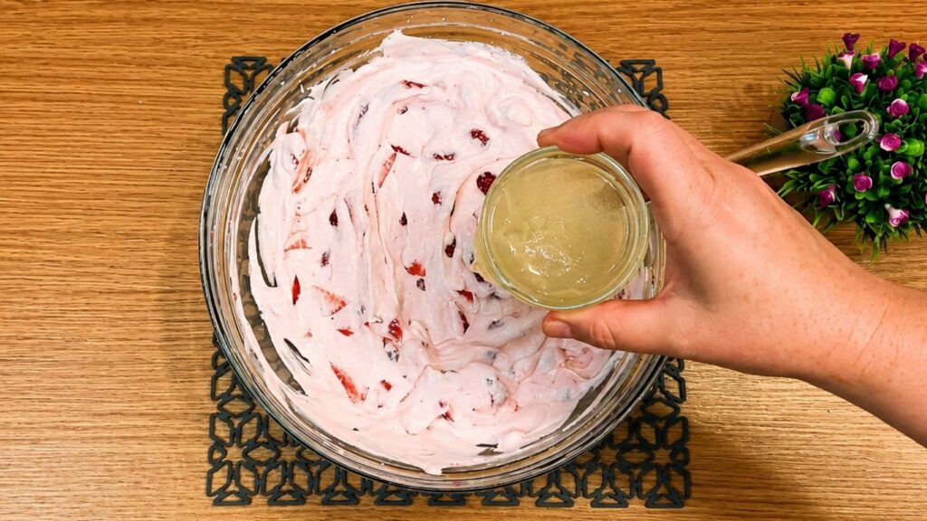 Pouring the whipped strawberry yogurt filling over the chilled cookie crust in the springform pan and smoothing the top into an even layer.