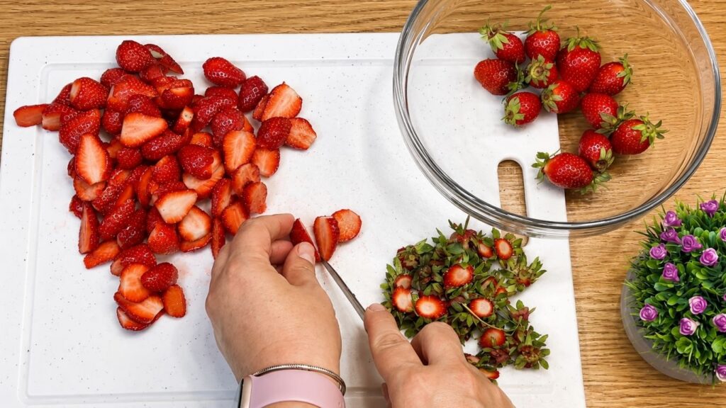 Slicing strawberries and arranging them neatly over the chilled no-bake strawberry yogurt cake before adding the glaze.